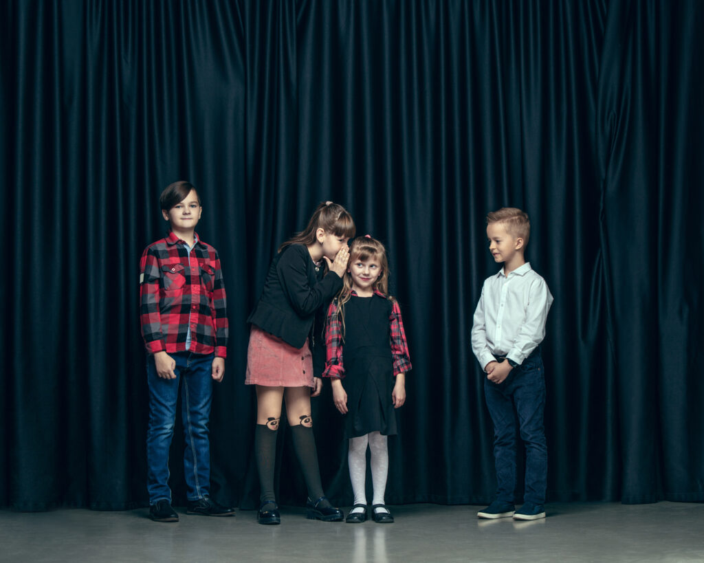 Cute stylish children on dark studio background. The beautiful teen girls and boy standing together